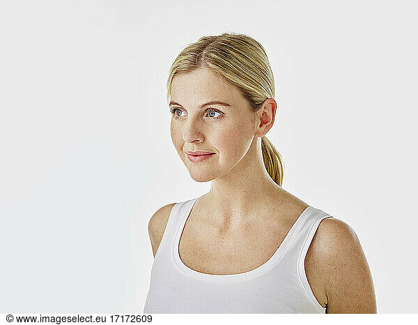 Young woman looking away while standing against white background
