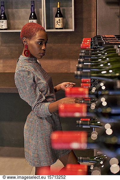 Young woman looking for a bottle of wine on her cellar