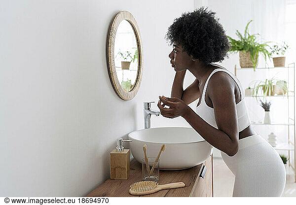 Young woman looking in mirror at bathroom