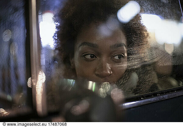 Young woman looking out car window at night