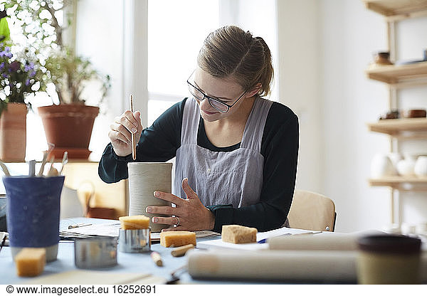 Young woman making earthenware in pottery class