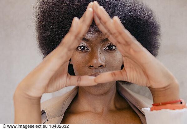 Young woman making triangle gesture with hands