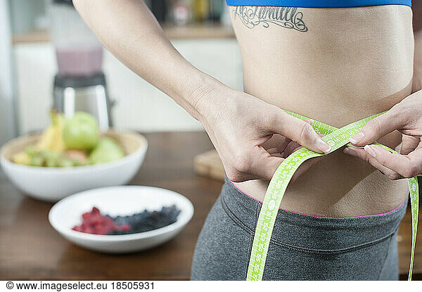 Young woman measuring waist with tape measure  Bavaria  Germany
