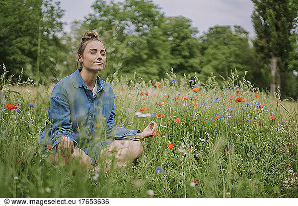 Young woman meditating in meadow