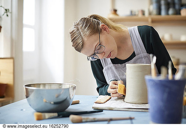 Young woman molding pot in pottery class