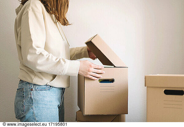Young woman moving cardboard boxes in new home