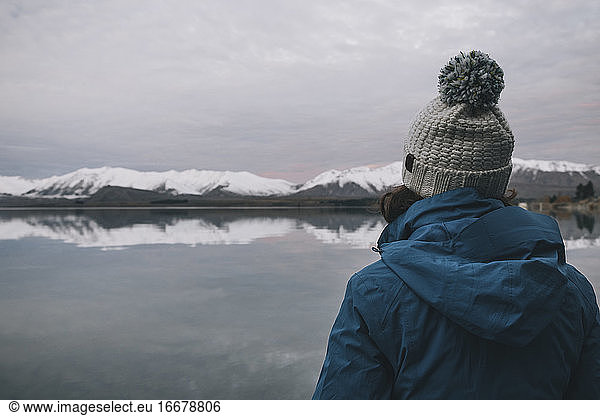 Young woman on a blue jacket stares at Lake Tekapo  Southern Alps