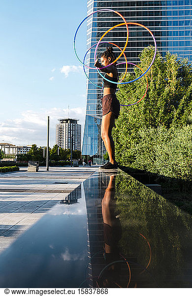 Young woman performing Hula Hoop dance with four rings in downtown