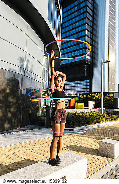 Young woman performing Hula Hoop dance with four rings in urban area