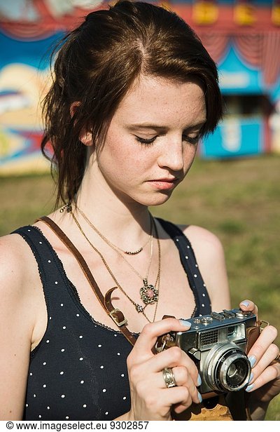 Young woman photographing on SLR camera at funfair
