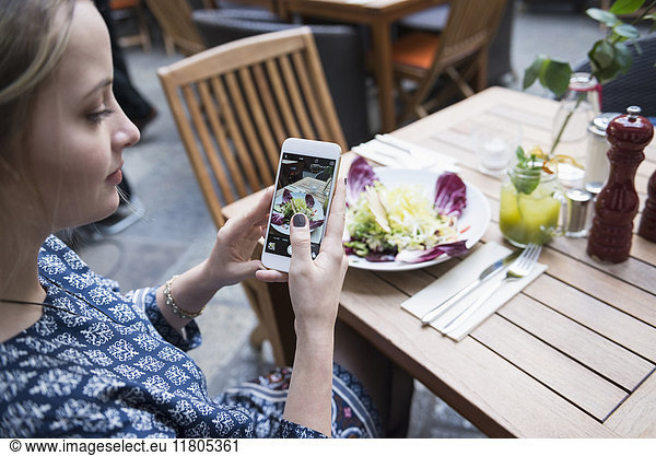 Young woman photographing salad