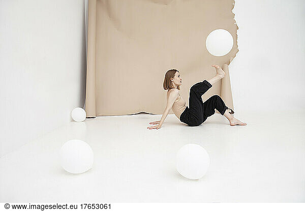 Young woman playing with balloon against brown backdrop