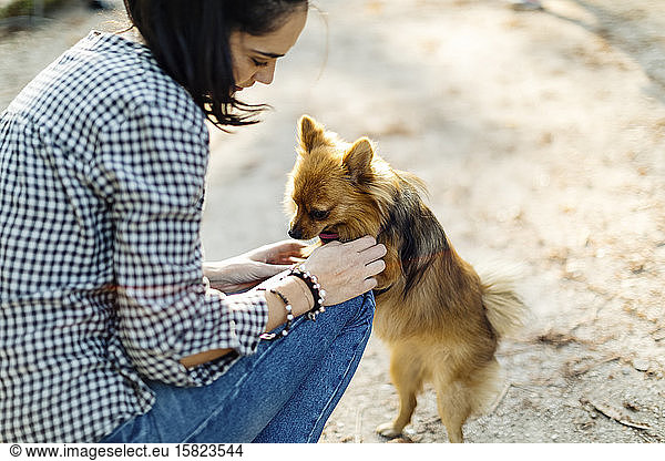 Young woman playing with dog outdoors