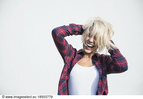 Young woman playing with her hairs and dancing in front of wall  Bavaria  Germany