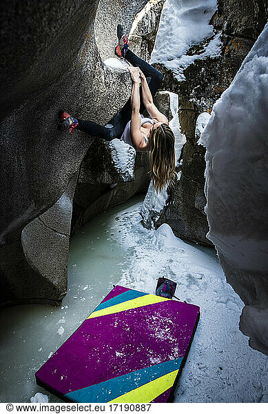 Young woman practicing bouldering on rock formation in ice caves at Independence Pass