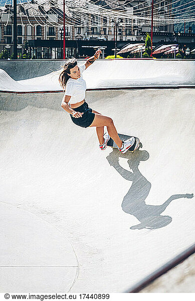 Young woman practicing skateboarding at skateboard park