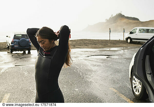 Young woman preparing to surf in coastal Oregon