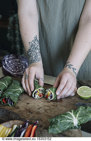 Young woman preparing vegan roll with vegetables on cutting board