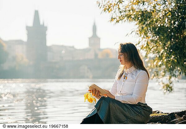 Young woman reading a book in the morning autumn sunny Prague