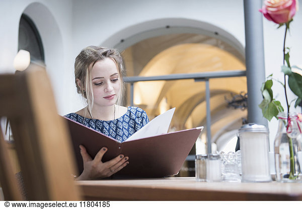 Young woman reading menu at restaurant