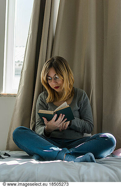 Young woman reads a book in her room