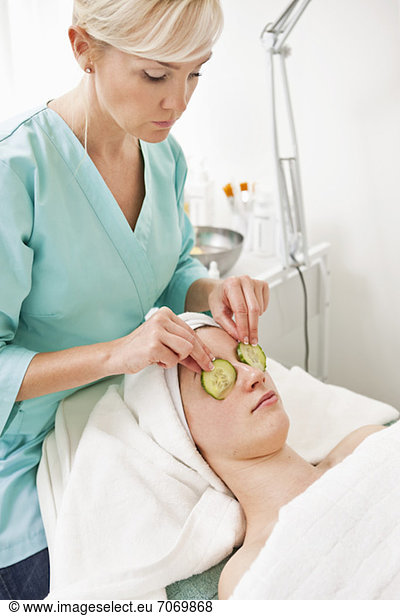Young woman receiving a facial from blond beautician in beauty spa
