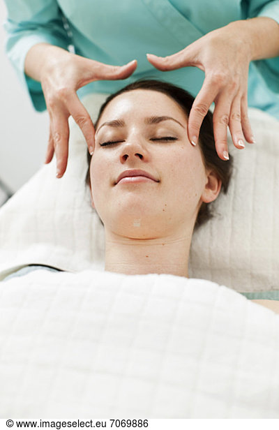 Young woman receiving face massage from masseur at beauty spa