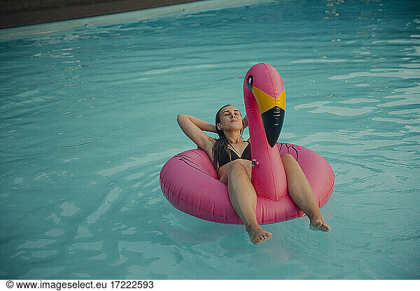 Young woman relaxing on a pink flamingo floating tire