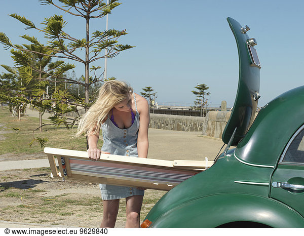 Young woman removing deck chair from car boot at beach  Altona  Melbourne  Victoria  Australia