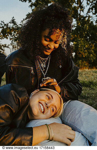 Young woman resting head on female friend's lap in park