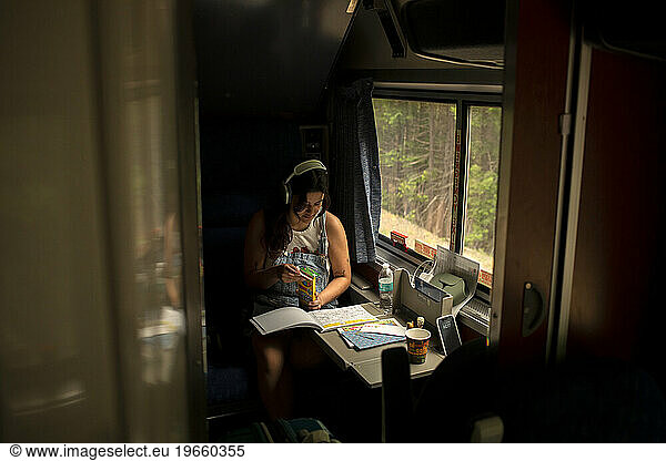 Young woman riding passenger train with coloring book