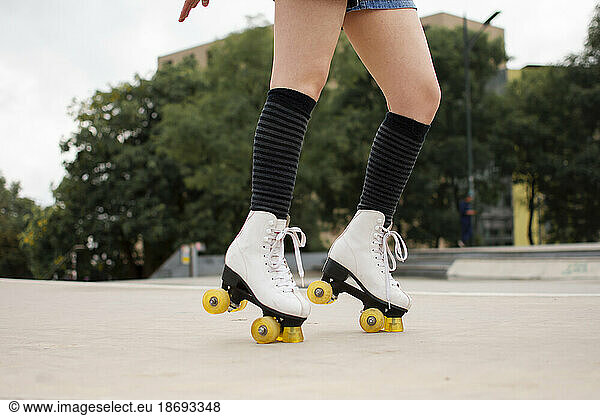 Young woman roller skating on footpath in park