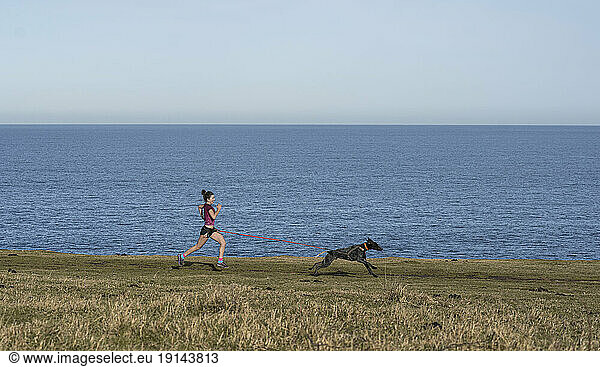 Young woman running with dog near sea