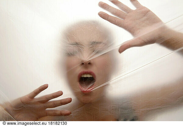 Young woman screaming behind foil