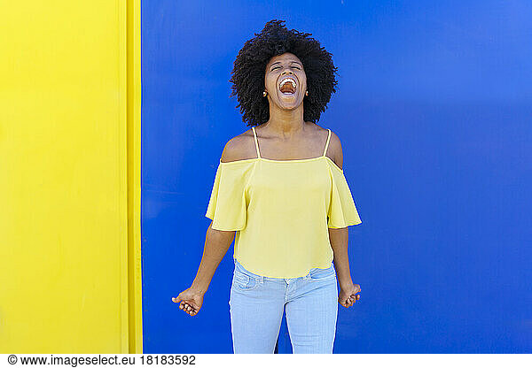 Young woman shouting in front of colorful wall