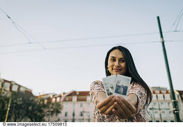 Young woman showing photographs of her in city