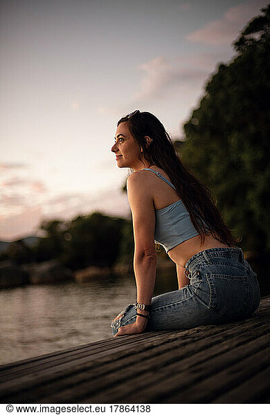 young woman sit in front of a lake and looking at the horizon