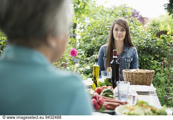 Young woman sitting down for meal in garden
