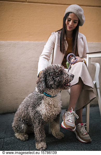 Young woman sitting with her dog in a cafe in the city