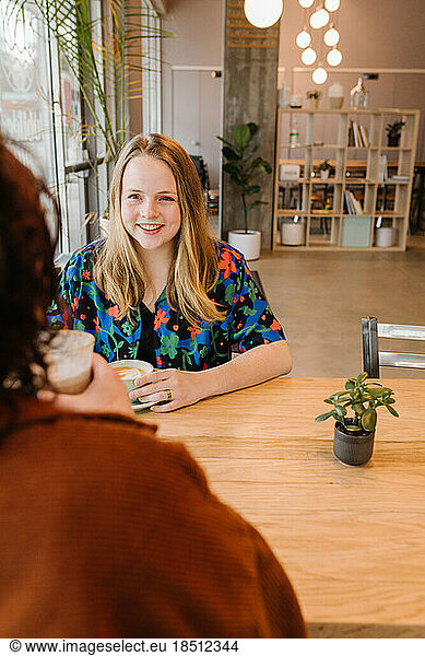young woman smiling at person sitting across table