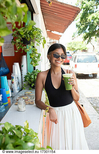 Young woman smiling holding healthy green juice
