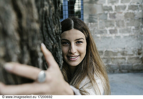 Young woman smiling while hugging tree