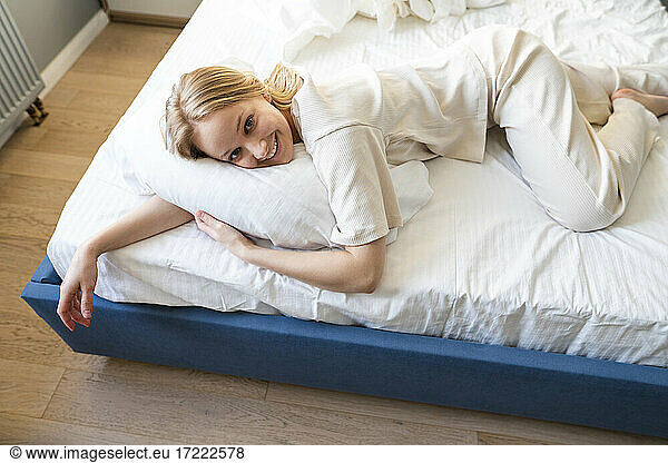 Young woman smiling while lying on bed at home