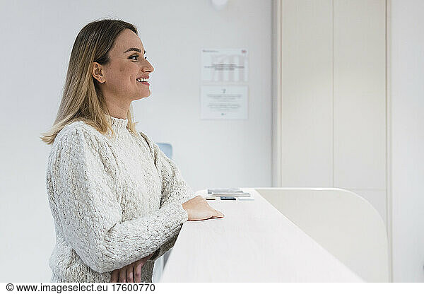 Young woman standing at reception desk in clinic