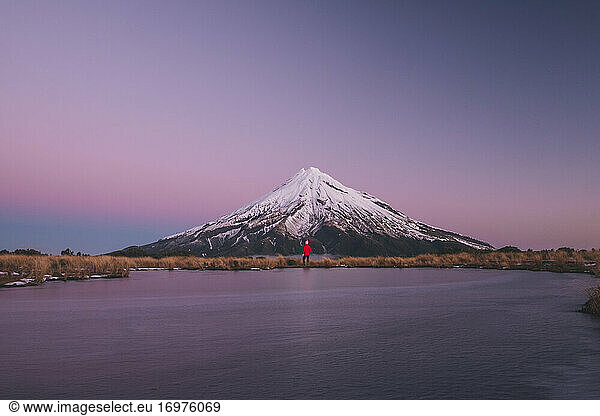 Young woman standing at the foot fo Mt Taranaki during early blue hour  New Zealand