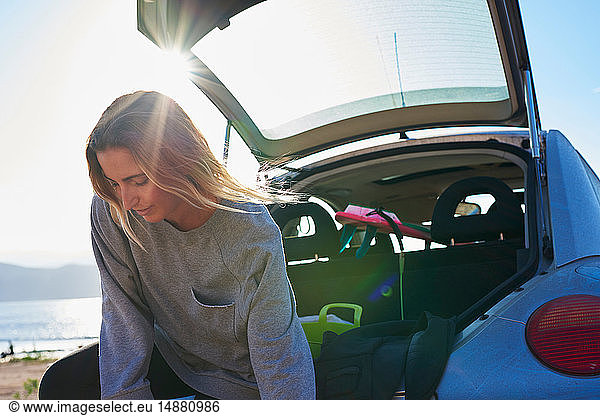 Young woman standing behind open car boot