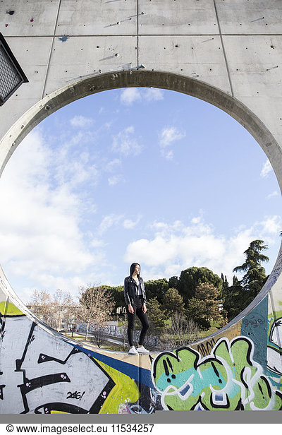 Young woman standing in a circle of a concrete wall