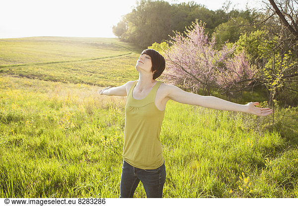 Young Woman Standing In Grassy Field In Spring.
