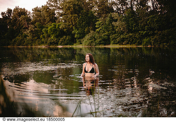 Young woman standing in lake against trees