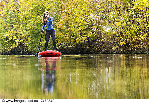 Young woman standing while paddleboarding on Rems river at Baden-Wurttemberg  Germany